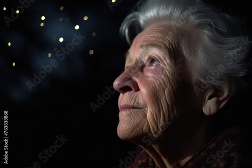 closeup of a senior woman at night looking out into the dark sky