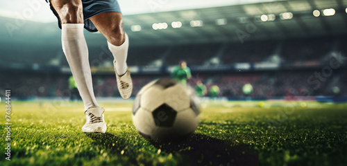 Male legs, football player in motion on filed dribbling ball, playing soccer at 3D stadium model with blurred tribune on background. Concept of professional sport, competition, tournament © master1305