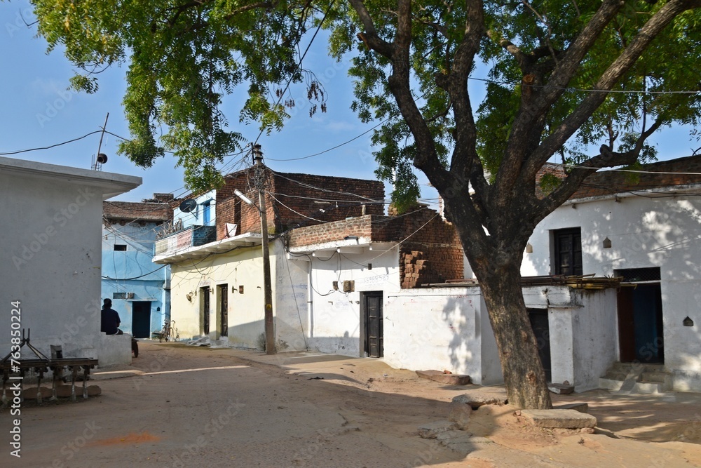 A narrow alley in a quaint village, lined with charming houses and cemented paths.