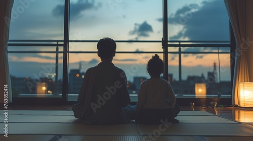 Silhouetted against a city skyline at dusk, two individuals practice meditation. The tranquility of the moment contrasts with the urban backdrop, symbolizing balance and inner peace.