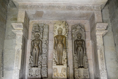 A finely detailed stone sculpture of a  Jain Tirthankara ADINATH,  with a serene expression, surrounded by ornate carvings  photo