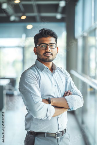 Portrait of confident Indian businessman standing with arms crossed in modern office