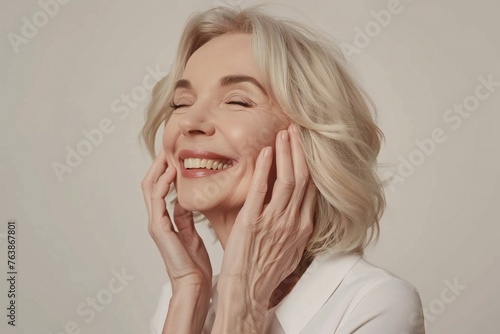 Happy beautiful blonde older mature lady touching facial skin, looking away with perfect toothy smile, laughing, enjoying elderly beauty care, thinking on good skincare result