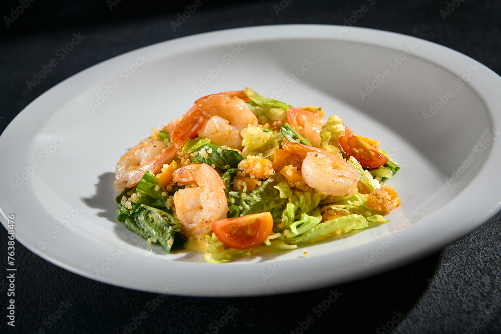 Shrimp salad with quinoa and mixed greens closeup, garnished with cherry tomatoes and a light dressing Shrimp salad with quinoa and mixed greens closeup, garnished with cherry tomatoes and a light dressing