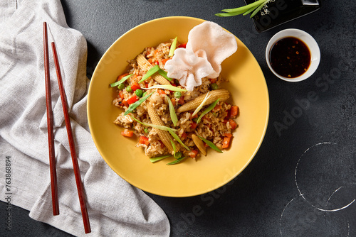 Top view of vegetable fried rice with baby corn and crunchy prawn crackers in a yellow bowl, Asian cuisine photo