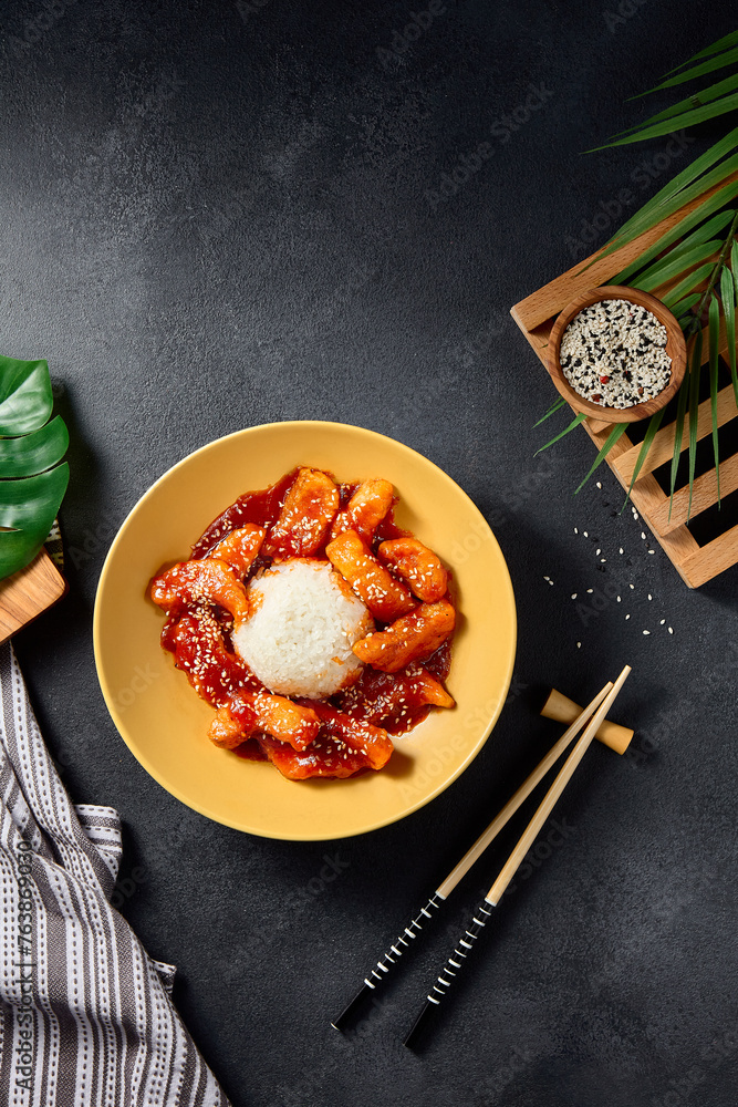 Top view of sweet and sour fish on a vibrant yellow plate, an Asian cuisine classic presented on a sleek black background Top view of sweet and sour fish on a vibrant yellow plate, an Asian cuisine classic presented on a sleek black background