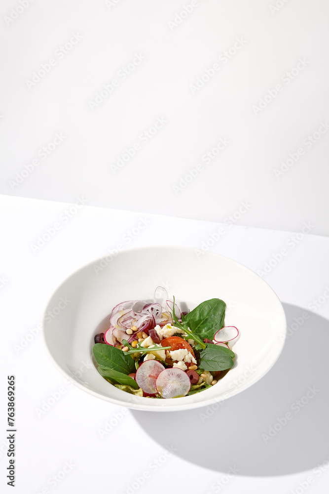 Greek salad isolated on a white background with crisp vegetables and feta cheese Greek salad isolated on a white background with crisp vegetables and feta cheese