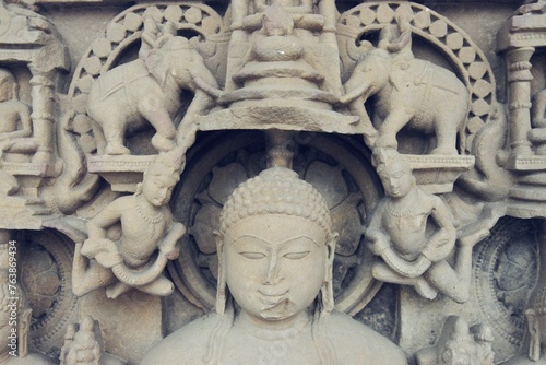 A finely detailed stone sculpture of a Jain Tirthankara ADINATH, with a serene expression, surrounded by ornate carvings photo