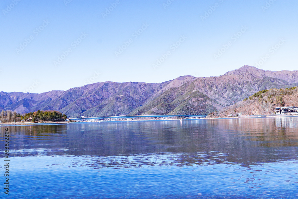 Landscape Bridge over lake and forest with mountain blue sky and bright sunlight in background. Dry forests in winter or autumn. Hills, lagoon of smoky mountain range covered.