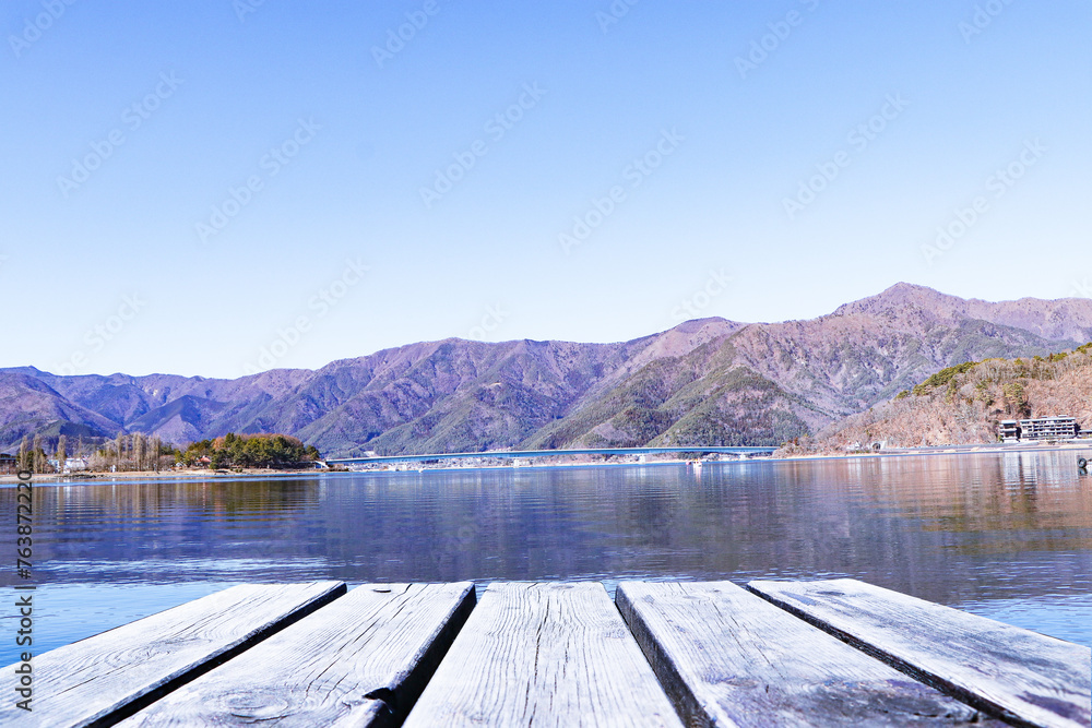 Empty blank wood plank or brown table. Landscape forest Lake with mountain blue sky and bright sunlight in background. Dry forests in winter or autumn. Hills, lagoon of smoky mountain range covered.