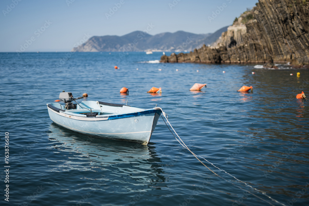 A wooden fishing boat sways peacefully on clean, clear water in sunny, calm weather - a coastal idyll