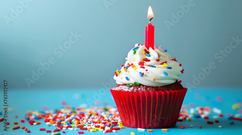 A festive birthday cupcake with a lit candle and colorful sprinkles.