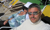 A caucasian couple sunbathing on a deck chair in winter