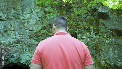 Local tourist standing in front of the opening of cave known as the site of the tomb of the Egyptian goddess Bastet, located in Strandzha Mountain, in Bulgaria. photo