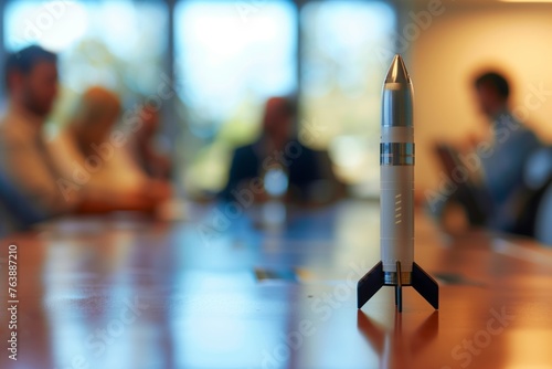rocket on conference table with meeting attendees blurred