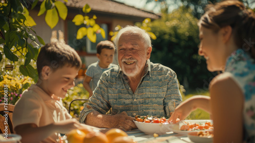 Elderly man and his family having fun at the backyard barbecue. Happy kids with grandpa enjoying food together in their garden during summer vacation