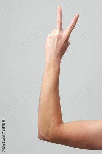 Male hand showing two fingers on gray background