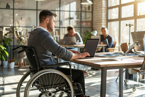 A wheelchair user is at a desk with a laptop, near a window and a houseplant