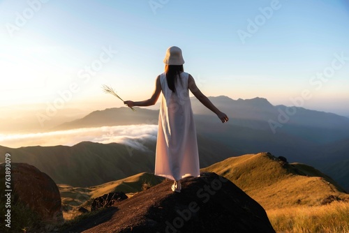 Happy young woman traveler relaxing and looking at the beautiful sunrise on the top of mountains, Travel lifestyle concept.Travel and summer Concept