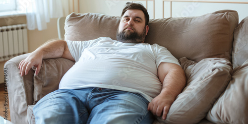 Fat lazy adult Man Relaxing on Couch at Home. An unshaven, overweight man with a big potbelly is lying on the couch, infantilized. photo