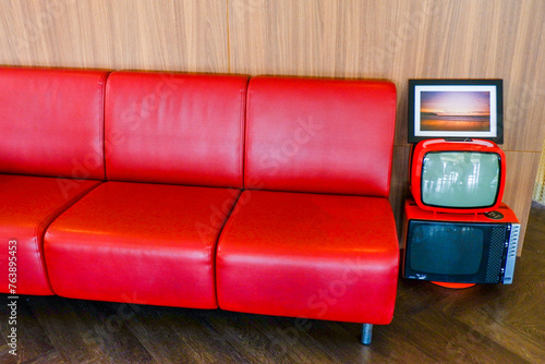 Red leather sofa and Vintage TV in living room at hotel or restaurant,Cozy wooden interior of restaurant,copy space, Comfortable modern dining place, contemporary design background..