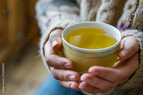 closeup of hands holding a warm cup of herbal tea