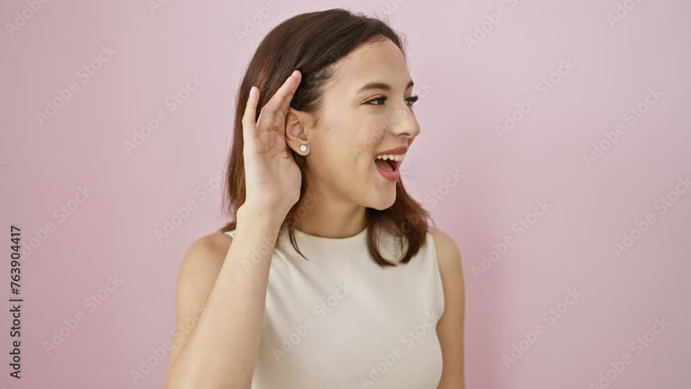 Joyful young hispanic woman in sleeveless t-shirt struggling with deafness hearing gossip over pink wall Joyful young hispanic woman in sleeveless t-shirt struggling with deafness hearing gossip over pink wall