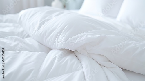 White folded duvet lying on white bed background. Preparing for winter season, household, domestic activities, hotel or home textile photo