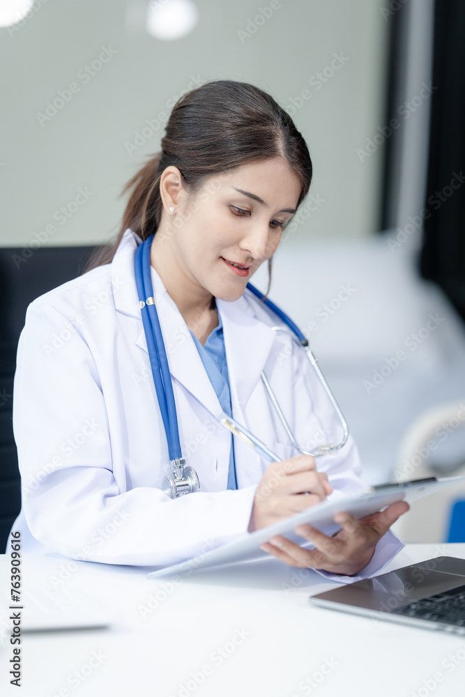 Portrait of mix race asian middle age female doctor in white lab coat and stethoscope while consult online in laptop. advice on good mental health management and medical treatment costs. Portrait of mix race asian middle age female doctor in white lab coat and stethoscope while consult online in laptop. advice on good mental health management and medical treatment costs.