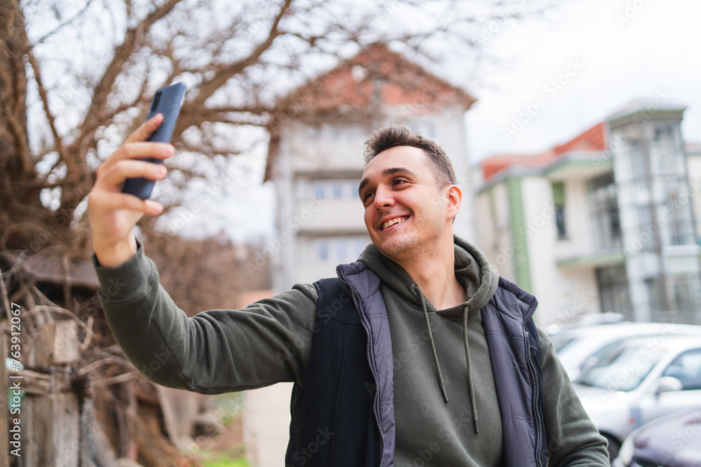 A man using and talking and taking selfie on his phone outside in the city during the day
A man using and talking and taking selfie on his phone outside in the city during the day