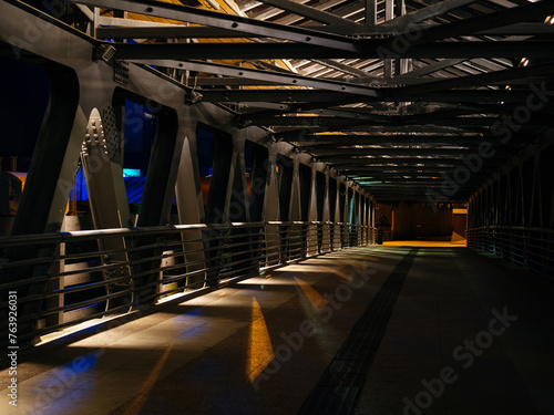 pedestrian bridge with metal structure in the city at night. Light and shadow