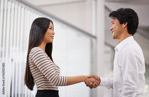 Business people, handshake and meeting with agreement for deal or proposal together at the office. Young asian man and woman holding or shaking hands for b2b, greeting or partnership at the workplace