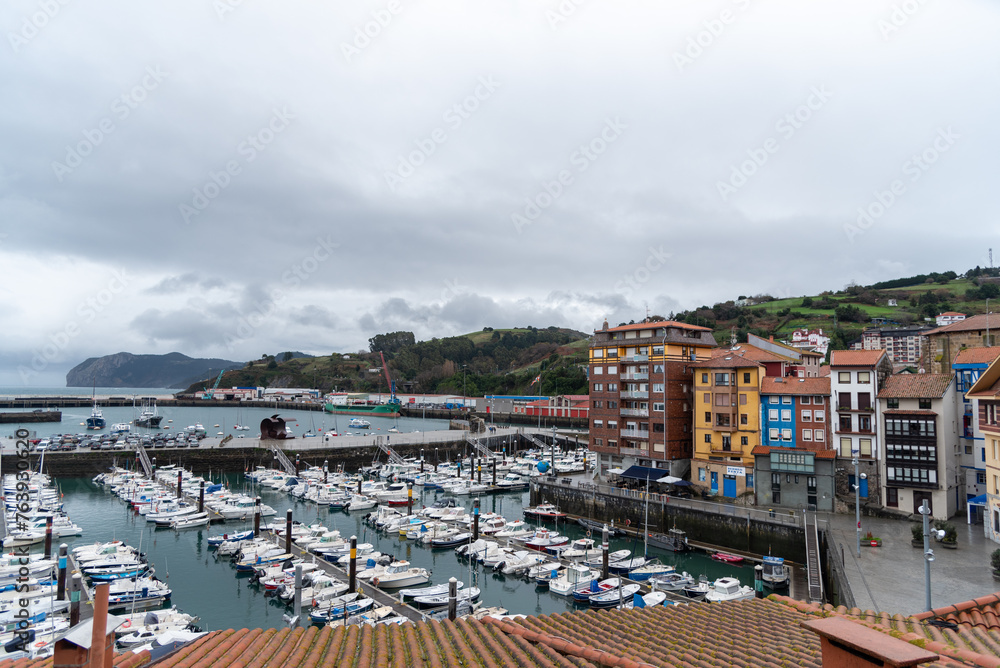 Panoramic view of the small harbour full of boats in the touristic coastal town of Bermeo on a cloudy day.