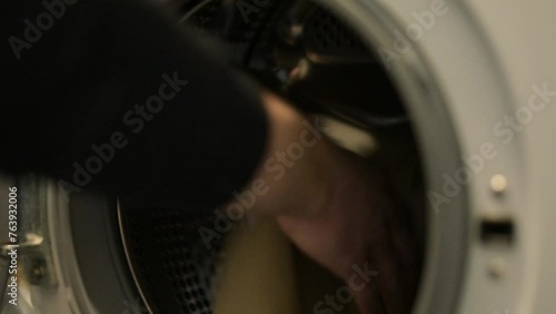 Male putting dirty clothes to washing machine for washing them. Washing clothes, laundry, daily routine, household work