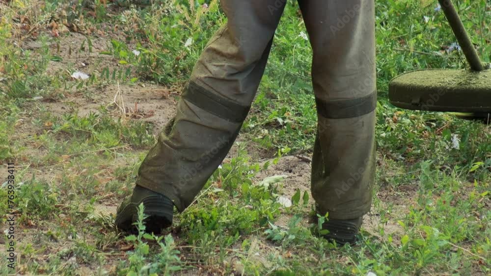 A farmer worker in a work uniform mows the grass with a gasoline trimmer on the lawn in the summer. Grass mowing services, slow motion A farmer worker in a work uniform mows the grass with a gasoline trimmer on the lawn in the summer. Grass mowing services, slow motion