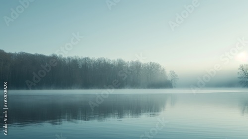 A serene lake enveloped in soft morning fog, with distant forested hills and the gentlest ripples on the water surface