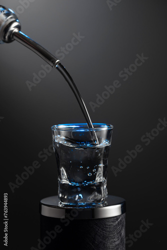 Vodka pouring from the bottle into a glass on a dark background.
