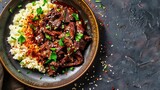 Sliced beef over cauliflower rice garnished with green onions and sesame seeds.