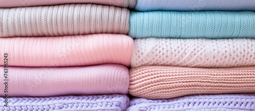 A creative arts display featuring a pile of sweaters in various tints and shades, including pink, magenta, and electric blue. The rectangleshaped stack showcases a mix of wool and linen textiles