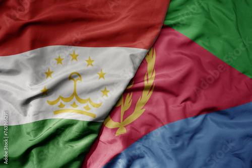 big waving national colorful flag of eritrea and national flag of tajikistan.