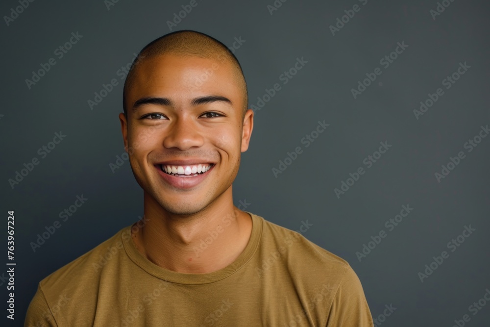 Fototapeta premium portrait of young smiling man of Asian appearance in yellow T-shirt on gray background