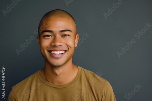 portrait of young smiling man of Asian appearance in yellow T-shirt on gray background © Руслан Галиуллин