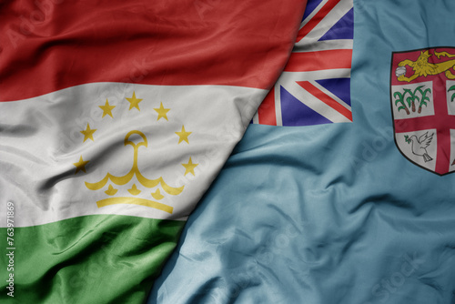 big waving national colorful flag of Fiji and national flag of tajikistan.