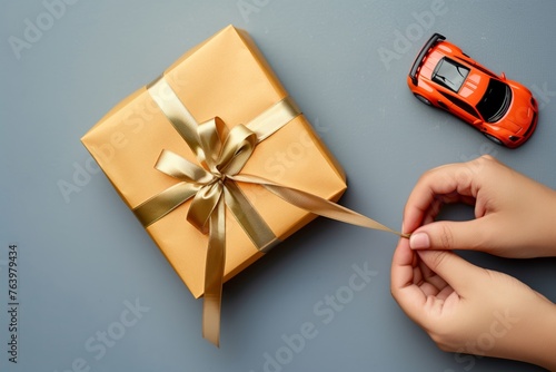hand tying ribbon on gift box with toy car visible © Alfazet Chronicles