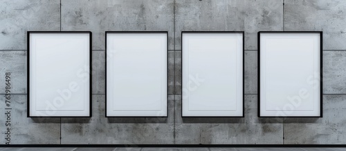 Four grey rectangular frames hang in parallel on a concrete wall facade, creating symmetry. The frames contrast with the muted tints and shades of the background, showcasing a sleek and modern design