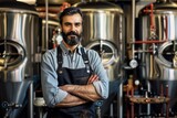 portrait of a brewmaster with arms crossed in front of brewing tanks