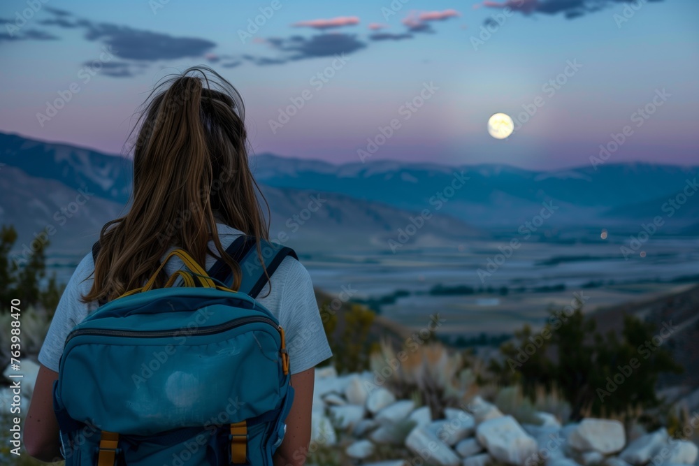 Fototapeta premium woman with backpack looking at moon over valley