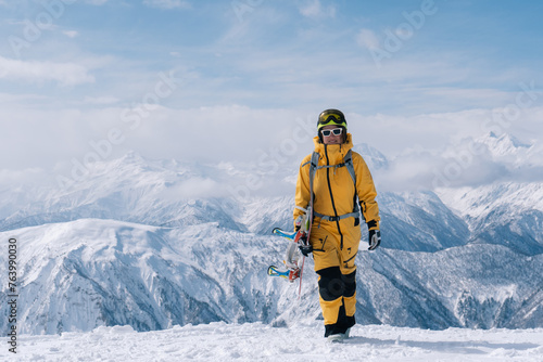 Snowboarder woman standing with snowboard in beautiful mountain peaks covered with snow on background