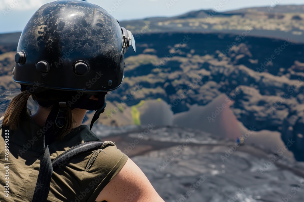tourist wearing helmet, peering over crater edge - obrazy, fototapety, plakaty 