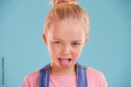Obraz na plátně Kid, portrait and tongue out in studio for silly, goofy and playful facial expression with blue background